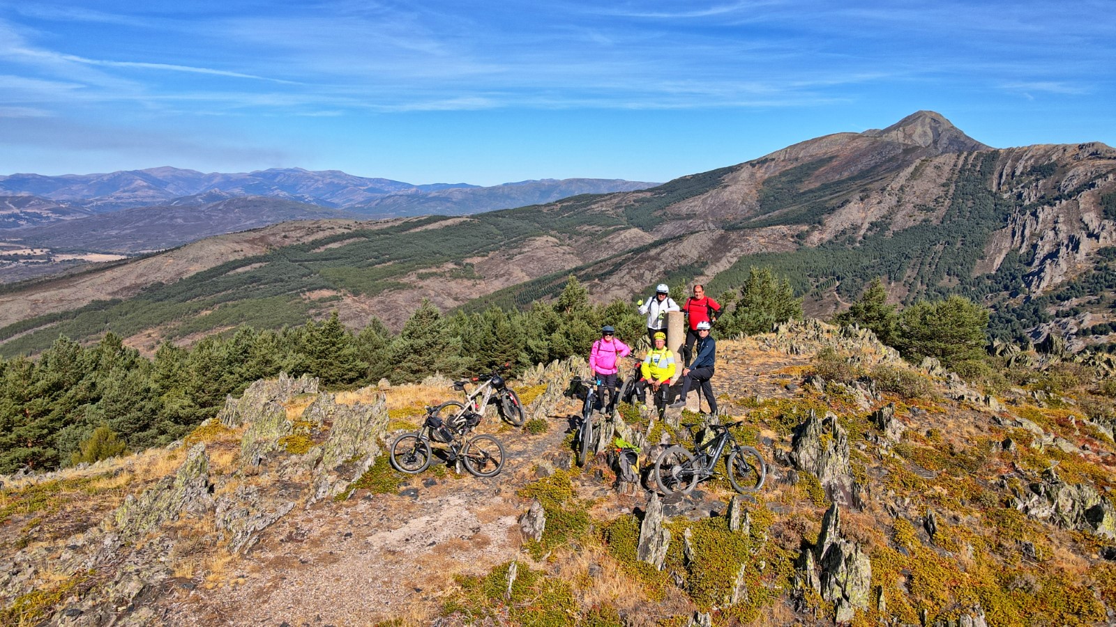 Ciclistas sentados observando el paisaje desde el Pico Almiruete
