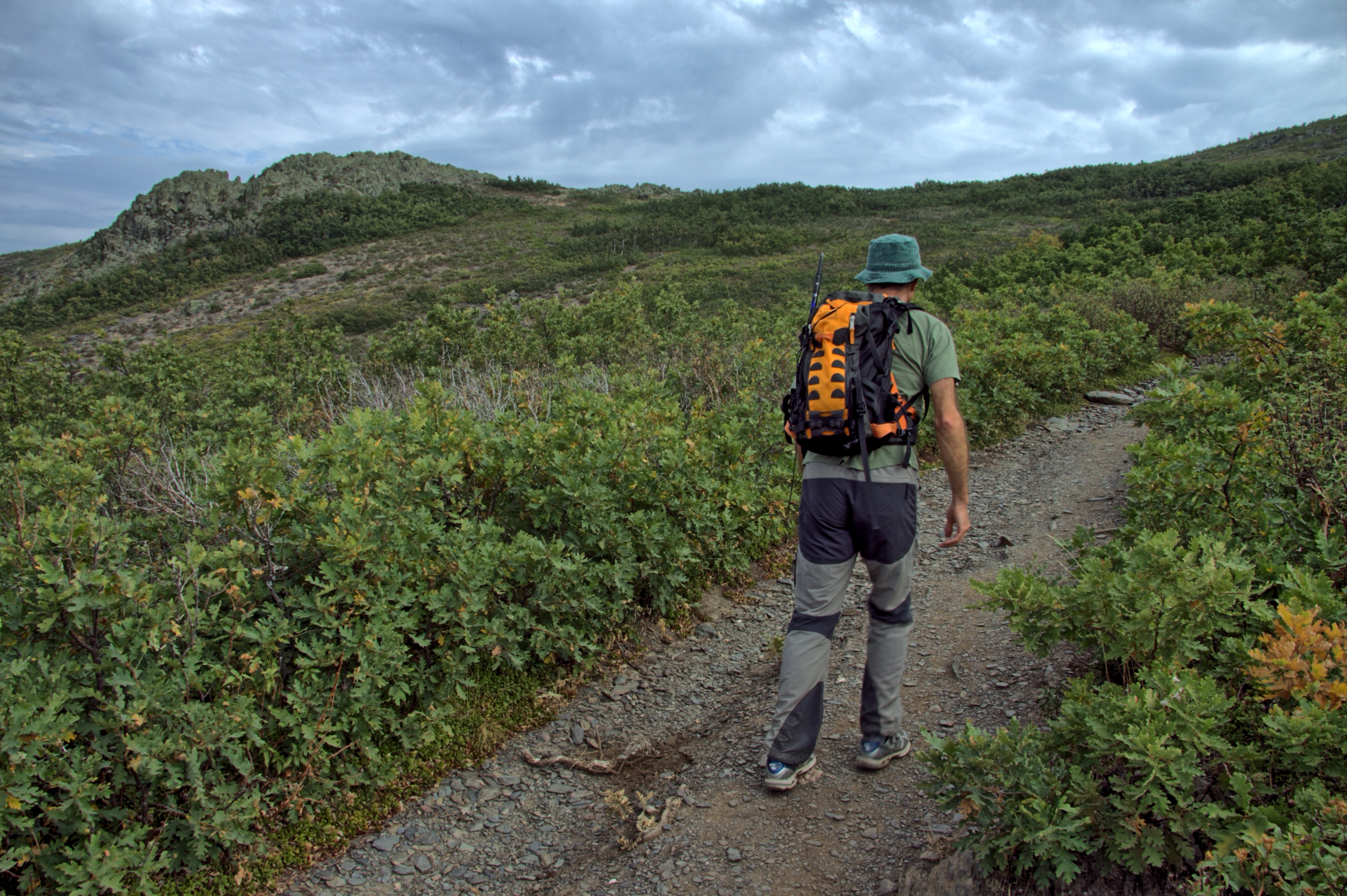 Un senderista asciende por el cm1 con peña Bernardo de fondo