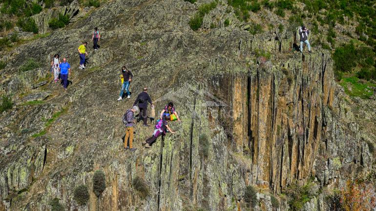 Los visitantes observan las cascadas del aljibe desde un resalte rocoso